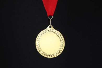 Photo of Golden medal with red ribbon on black background