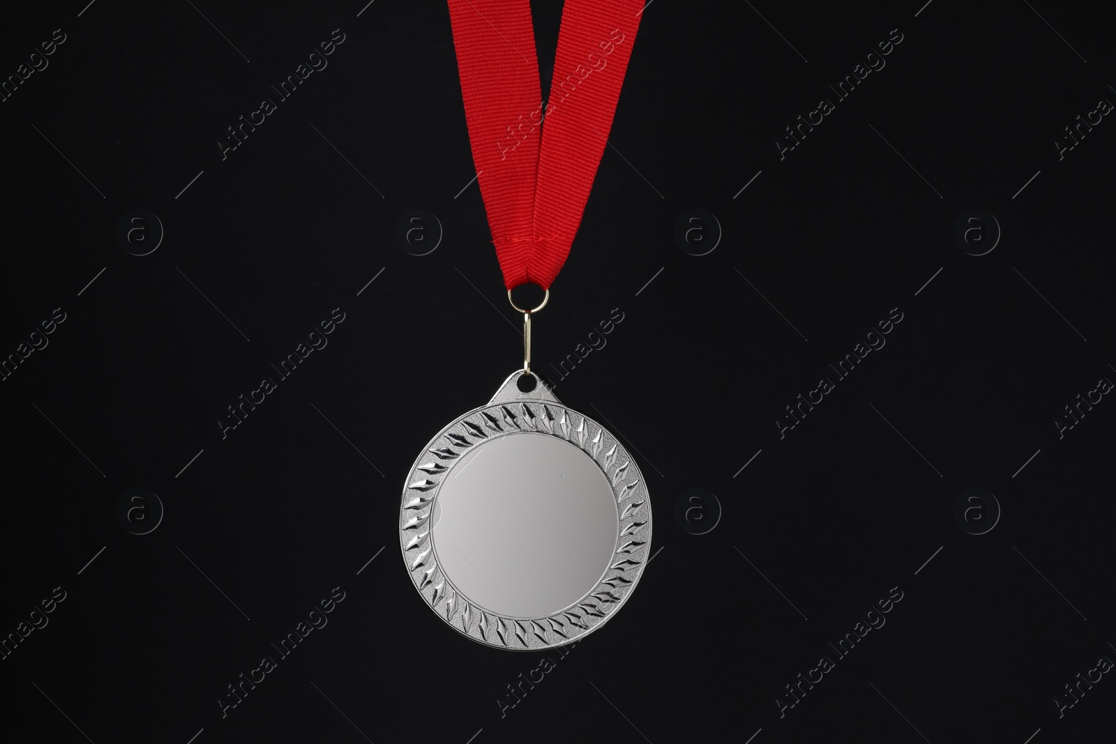 Photo of Silver medal with red ribbon on black background