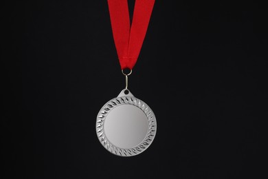 Photo of Silver medal with red ribbon on black background