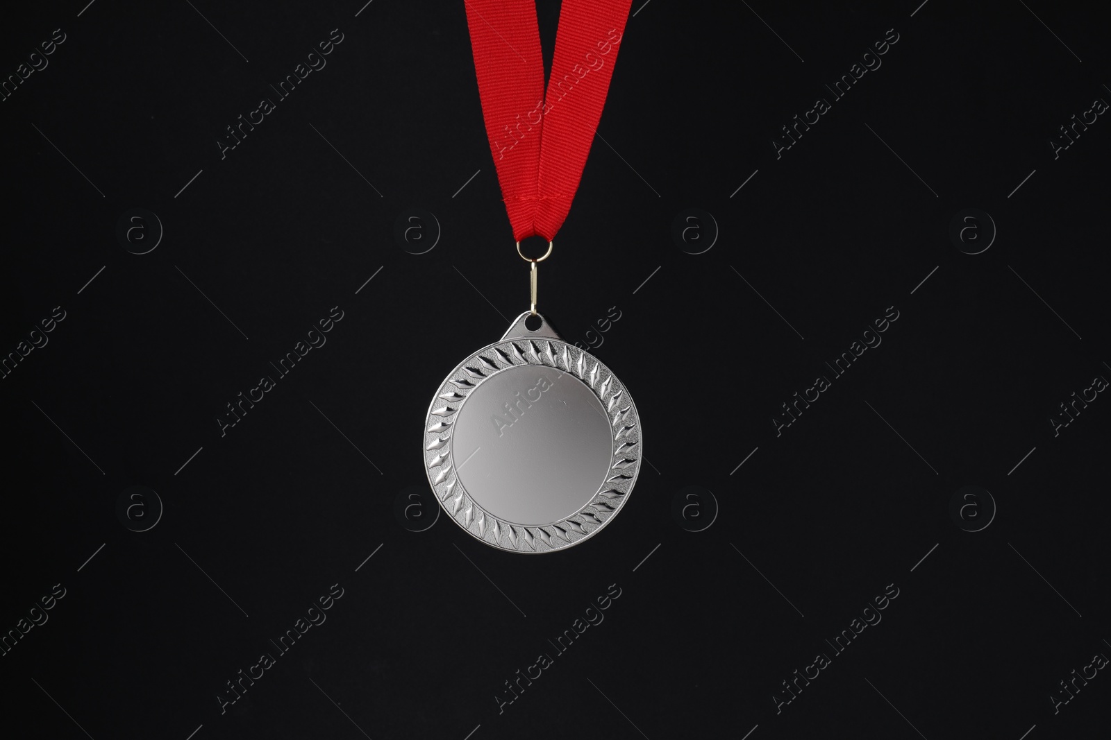 Photo of Silver medal with red ribbon on black background