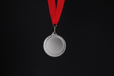 Photo of Silver medal with red ribbon on black background