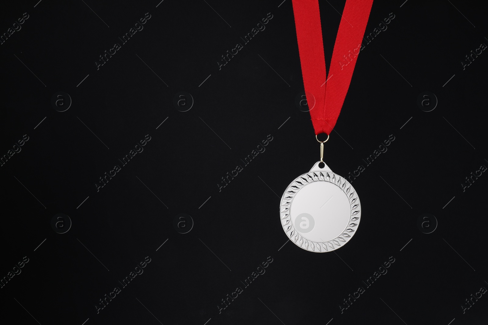 Photo of Silver medal with red ribbon on black background, space for text