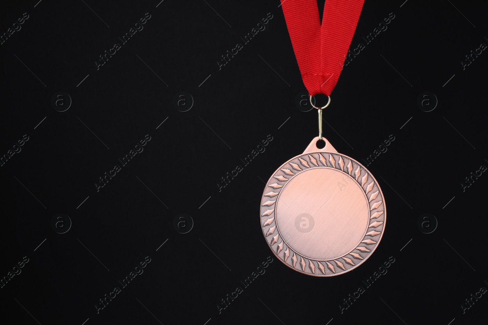 Photo of Bronze medal with red ribbon on black background, space for text