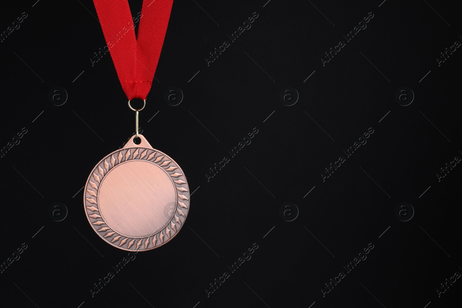 Photo of Bronze medal with red ribbon on black background, space for text