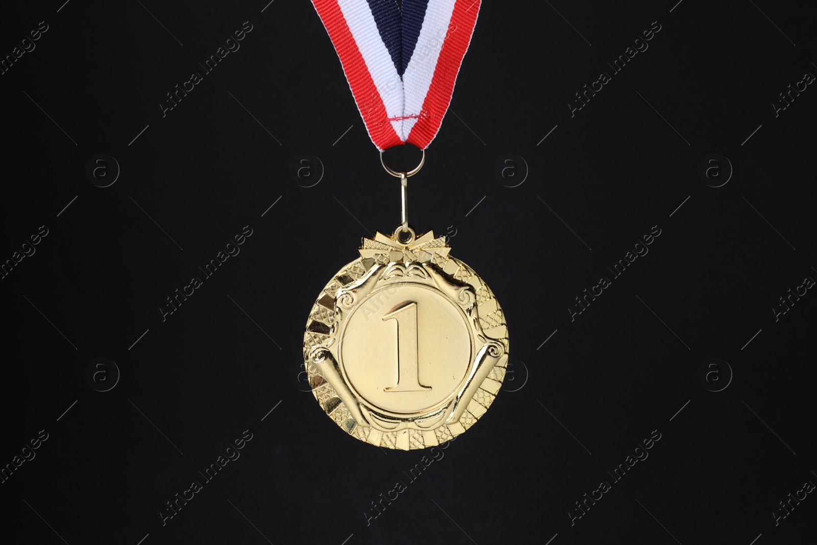 Photo of Golden medal with striped ribbon on black background