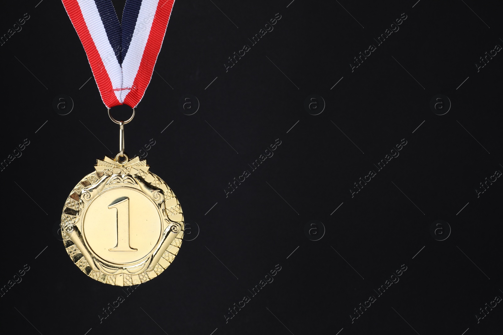 Photo of Golden medal with striped ribbon on black background, space for text