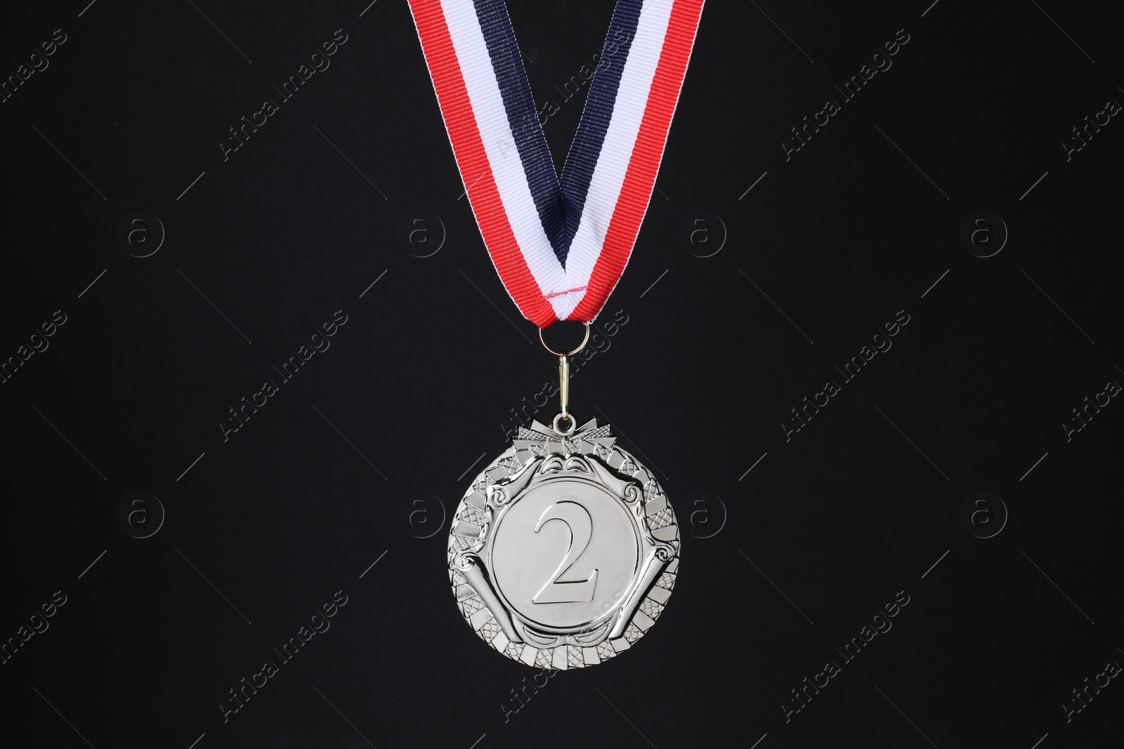 Photo of Silver medal with striped ribbon on black background