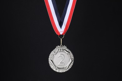 Photo of Silver medal with striped ribbon on black background