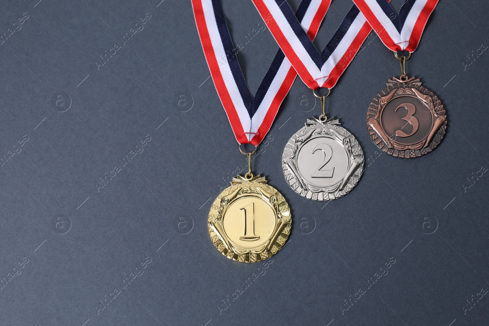 Photo of Golden, silver and bronze medals on grey background, above view. Space for text