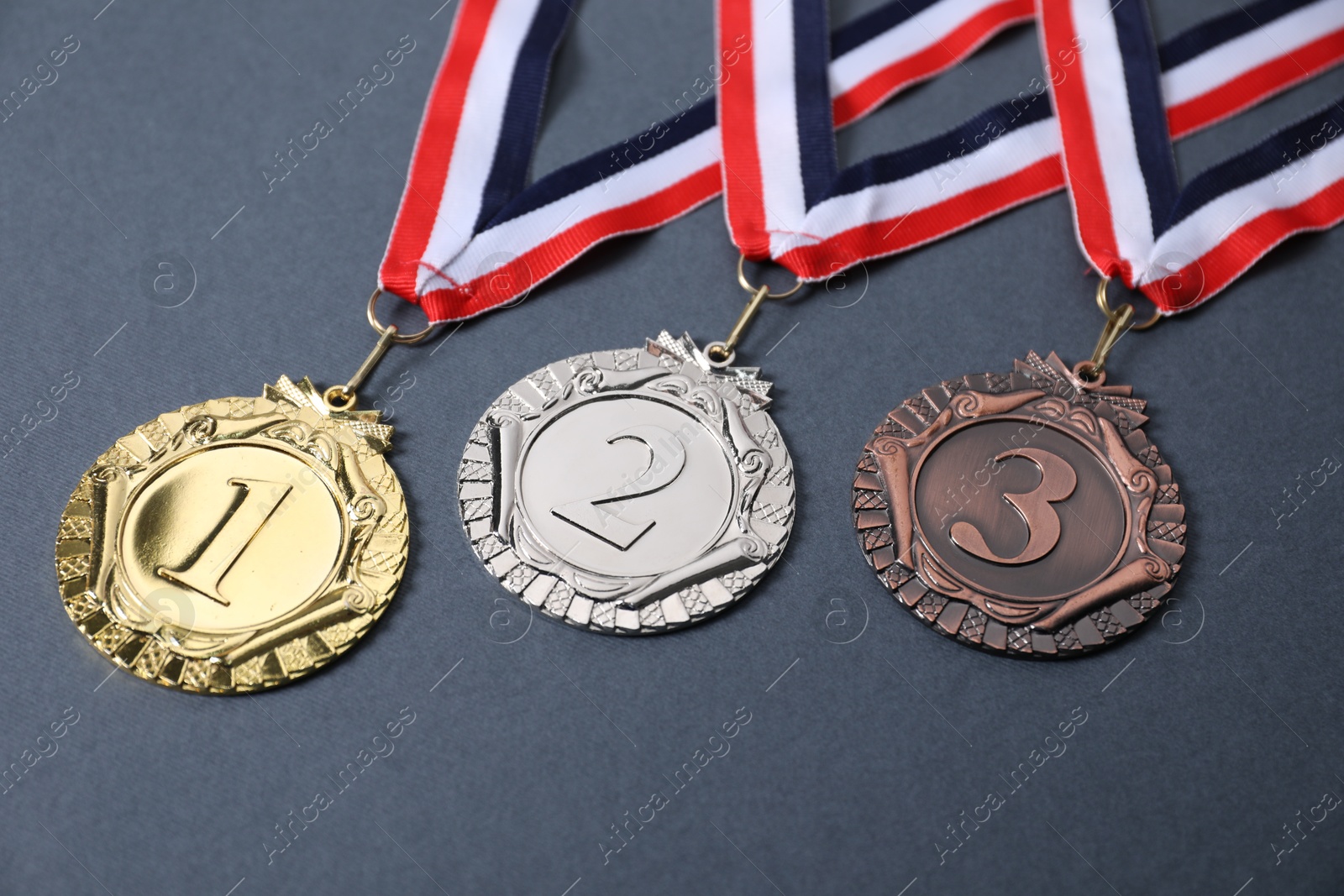 Photo of Golden, silver and bronze medals on grey background, closeup