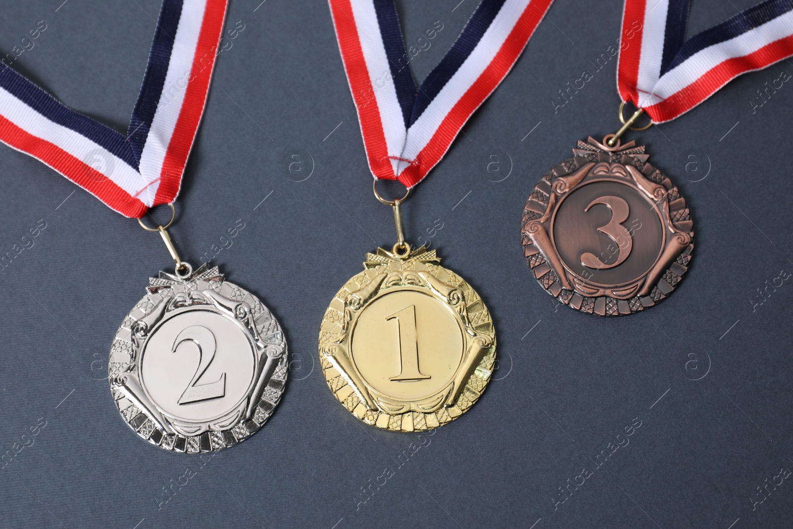 Photo of Golden, silver and bronze medals on grey background, top view