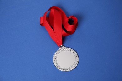 Photo of Silver medal with red ribbon on blue background, above view