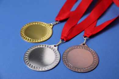 Photo of Golden, silver and bronze medals on blue background, closeup