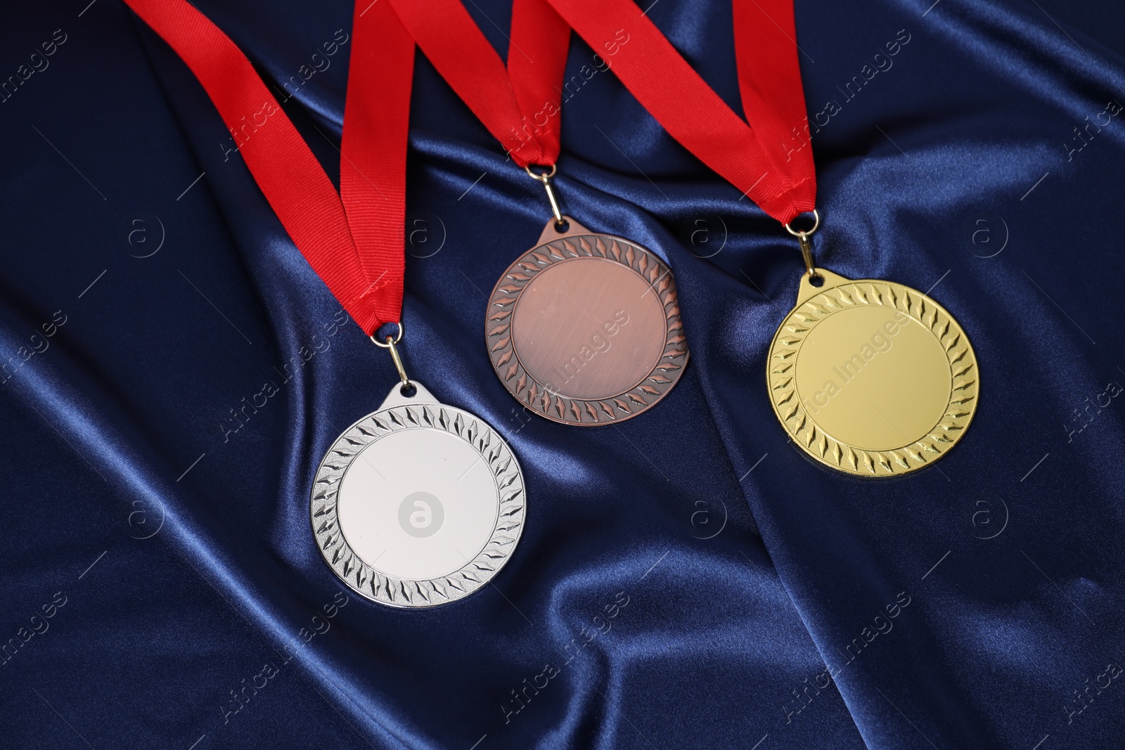 Photo of Golden, silver and bronze medals on blue fabric, above view