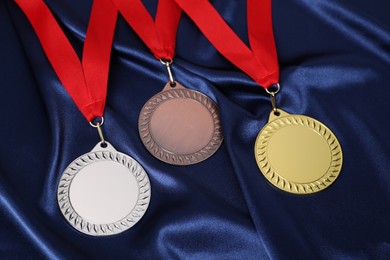 Photo of Golden, silver and bronze medals on blue fabric, closeup