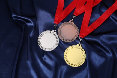 Photo of Golden, silver and bronze medals on blue fabric, above view