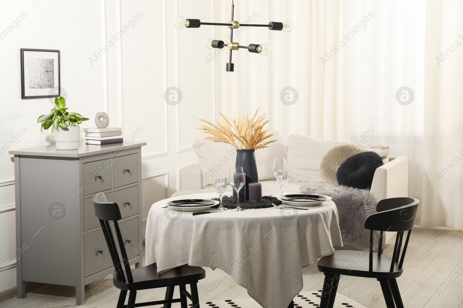 Photo of Stylish table setting with beautiful dishware and black chairs in dining room