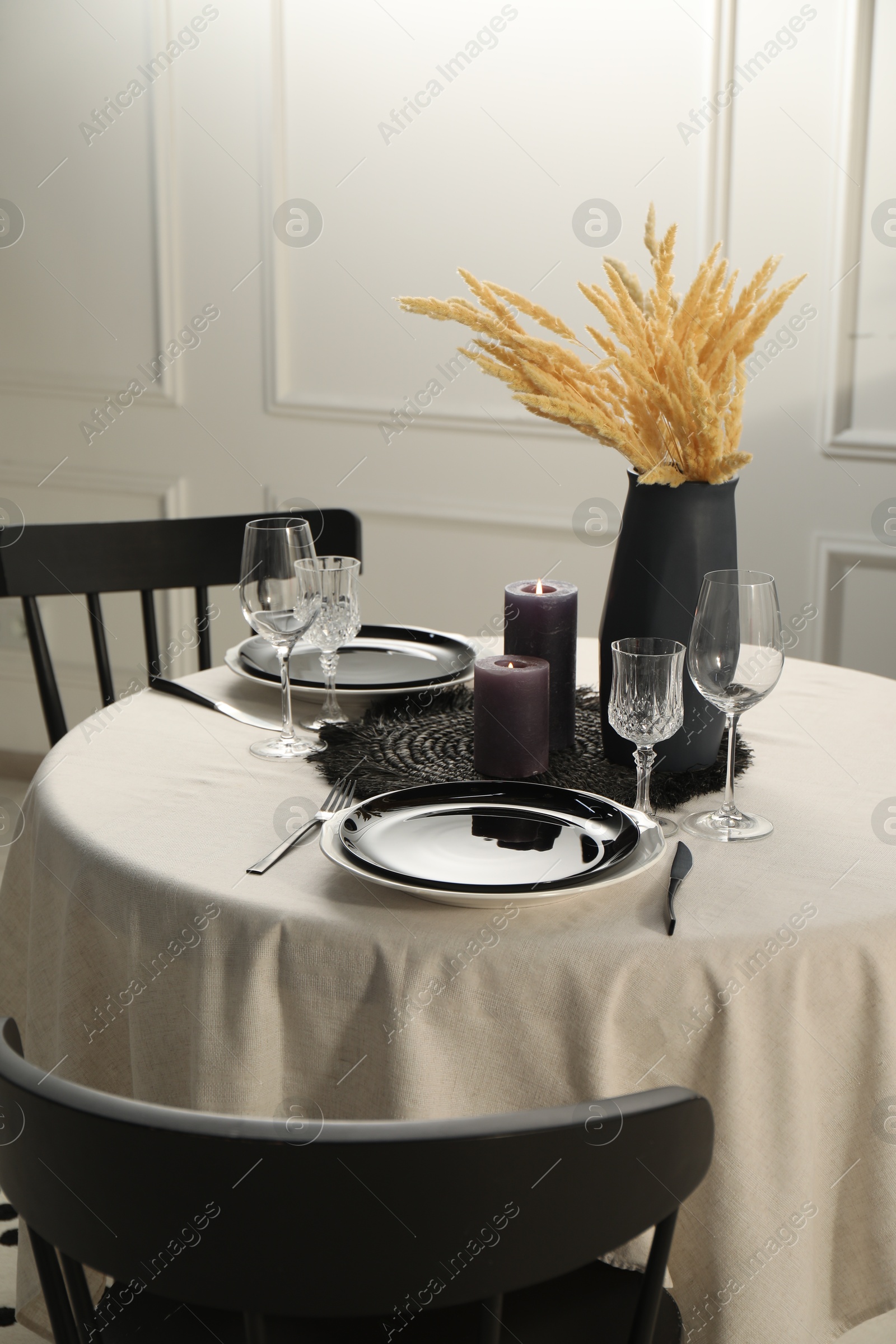 Photo of Stylish table setting with beautiful dishware and black chairs in dining room