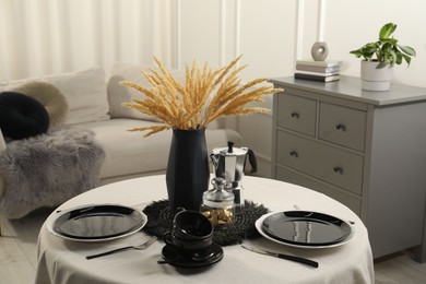 Photo of Stylish table setting with black dishware in dining room