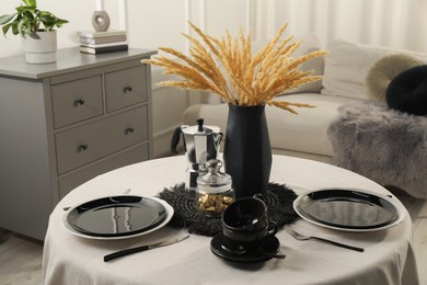 Photo of Stylish table setting with black dishware in dining room