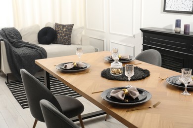 Photo of Stylish table setting with black dishware in dining room