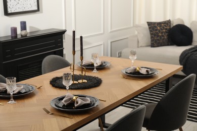 Photo of Stylish table setting with black dishware in dining room