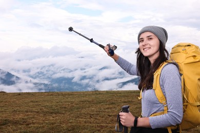 Photo of Young hiker with trekking poles and backpack in mountains outdoors, space for text