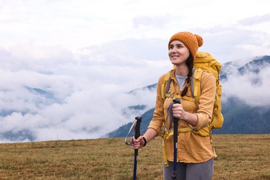 Photo of Young hiker with trekking poles and backpack in mountains outdoors, space for text