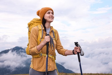 Photo of Young hiker with trekking poles and backpack in mountains outdoors