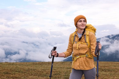 Photo of Young hiker with trekking poles and backpack in mountains outdoors, space for text