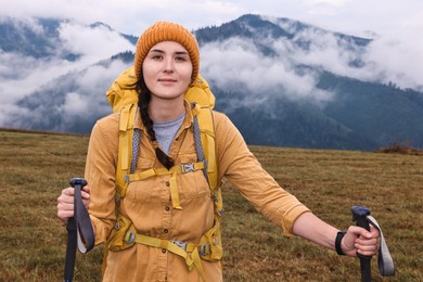 Photo of Young hiker with trekking poles and backpack in mountains outdoors