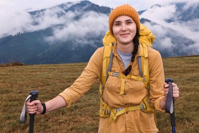 Young hiker with trekking poles and backpack in mountains outdoors