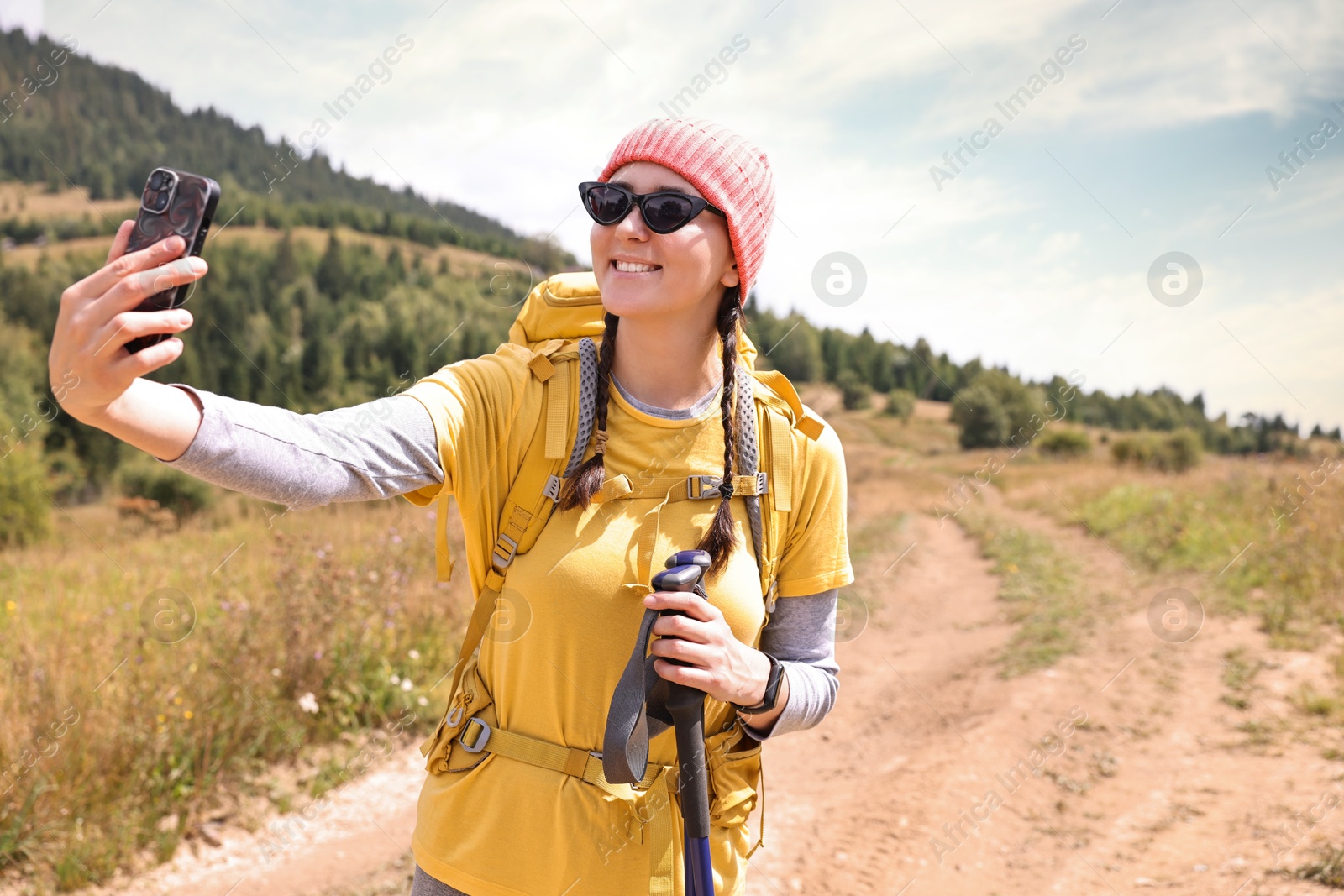 Photo of Young hiker with backpack taking selfie outdoors, space for text