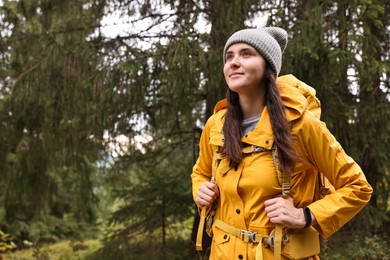 Photo of Young hiker with backpack in forest, space for text