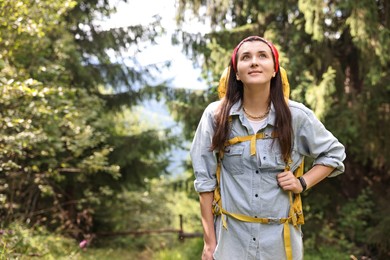 Photo of Young hiker with backpack looking at something in forest, low angle view