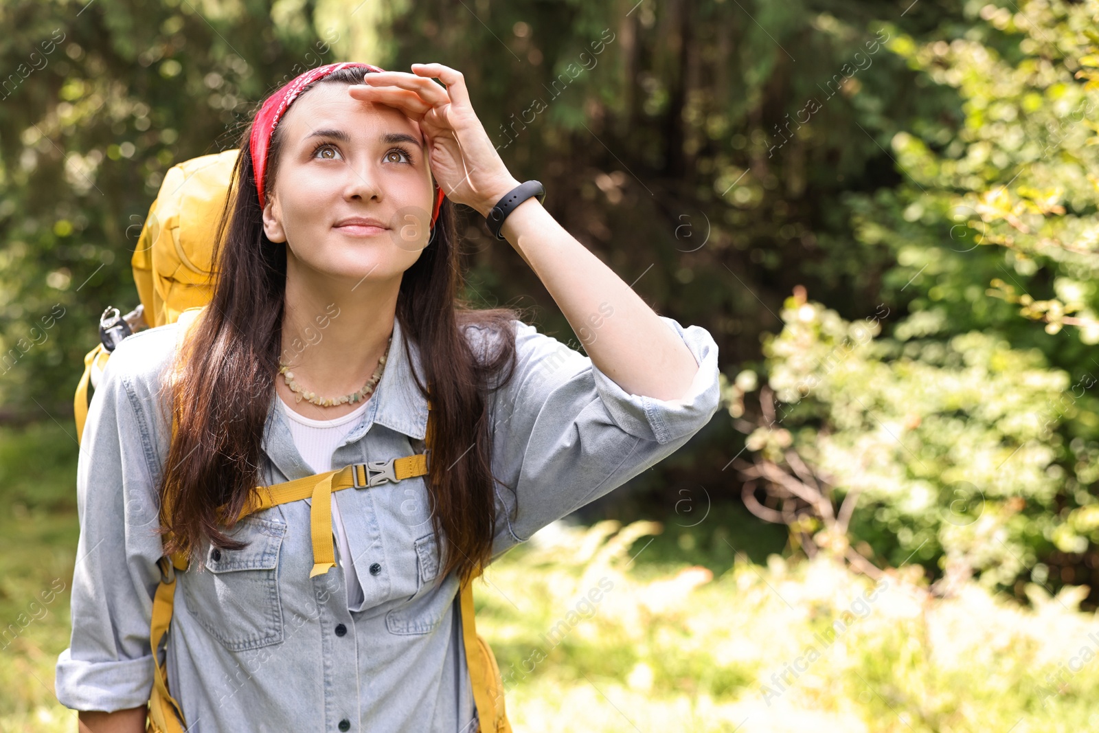 Photo of Young hiker with backpack looking at something in forest