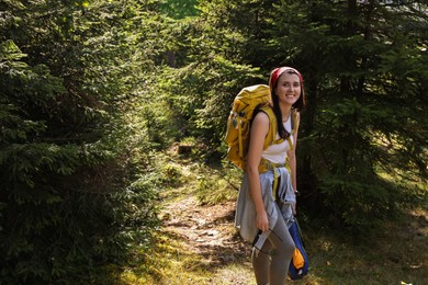 Young hiker with backpack, packed tent and sunglasses in forest