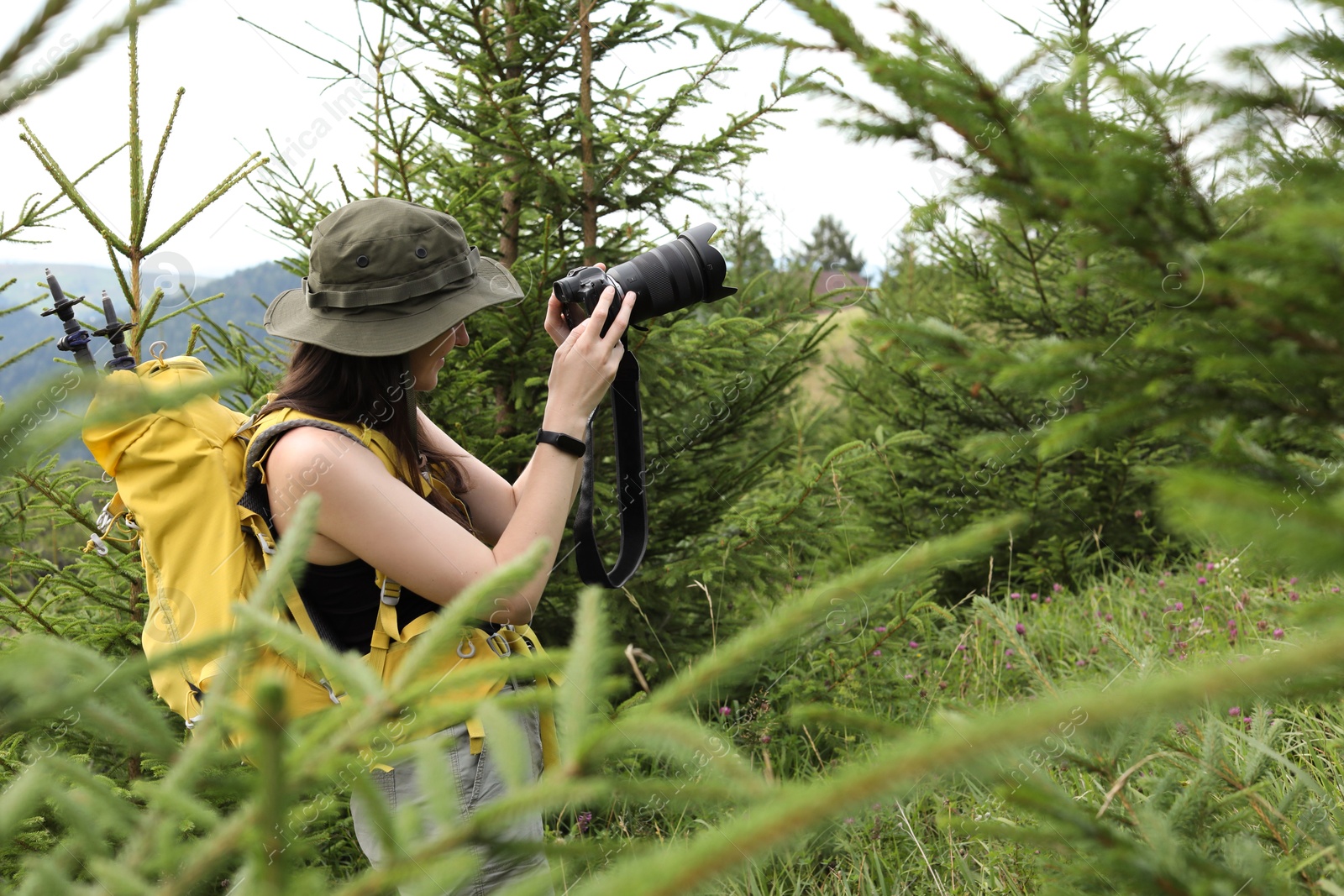 Photo of Young hiker with backpack and camera in forest, space for text