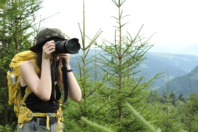 Photo of Young hiker with backpack and camera in forest, space for text