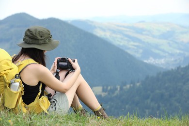 Photo of Young hiker with backpack and camera in mountains, back view. Space for text