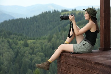 Young hiker with camera in mountains, space for text