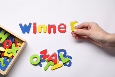 Photo of Woman making word Winner with magnetic letters on white background, top view