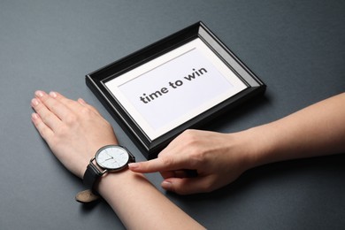 Photo of Woman pointing and watch and frame with words Time To Win on grey background, closeup