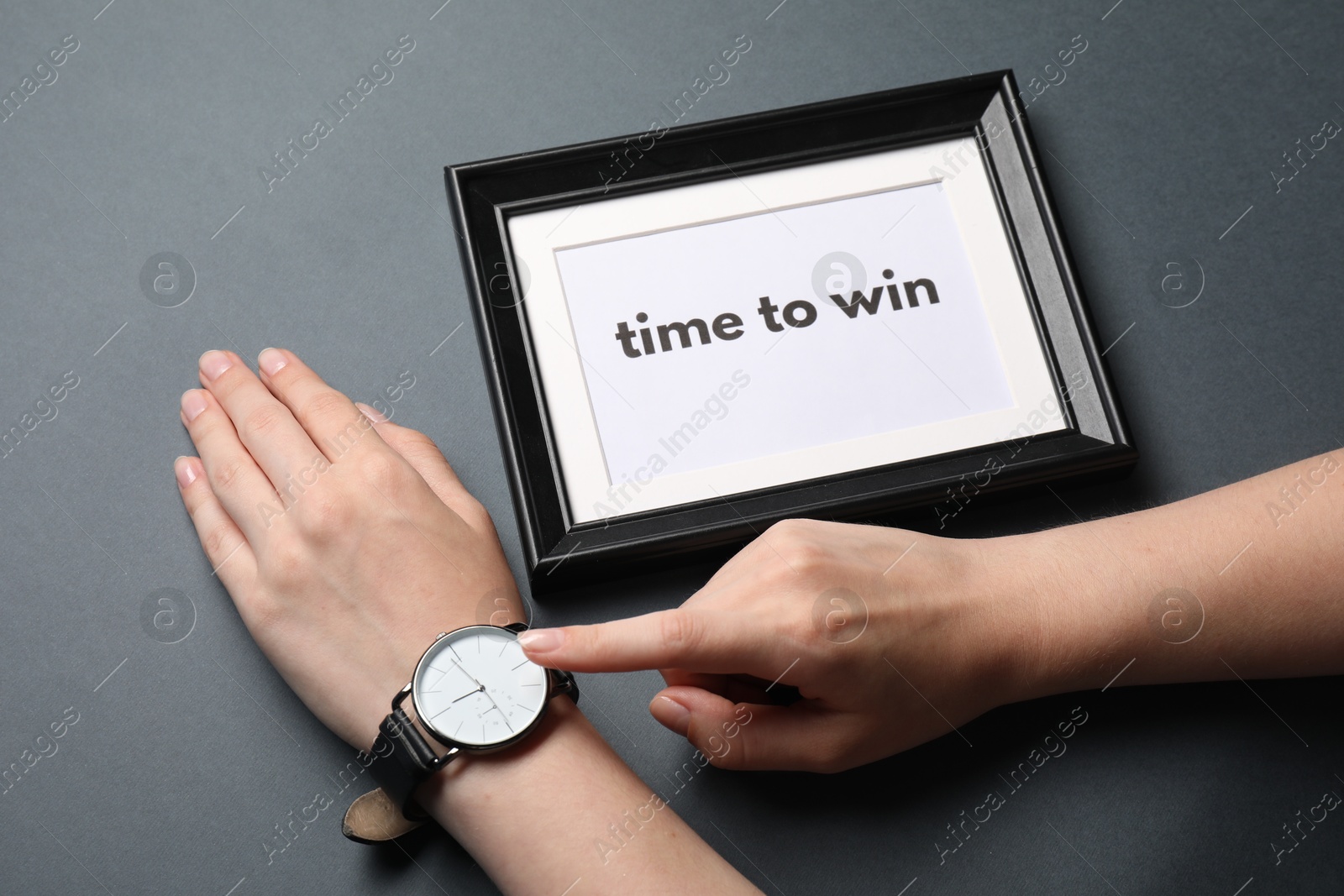 Photo of Woman pointing and watch and frame with words Time To Win on grey background, closeup