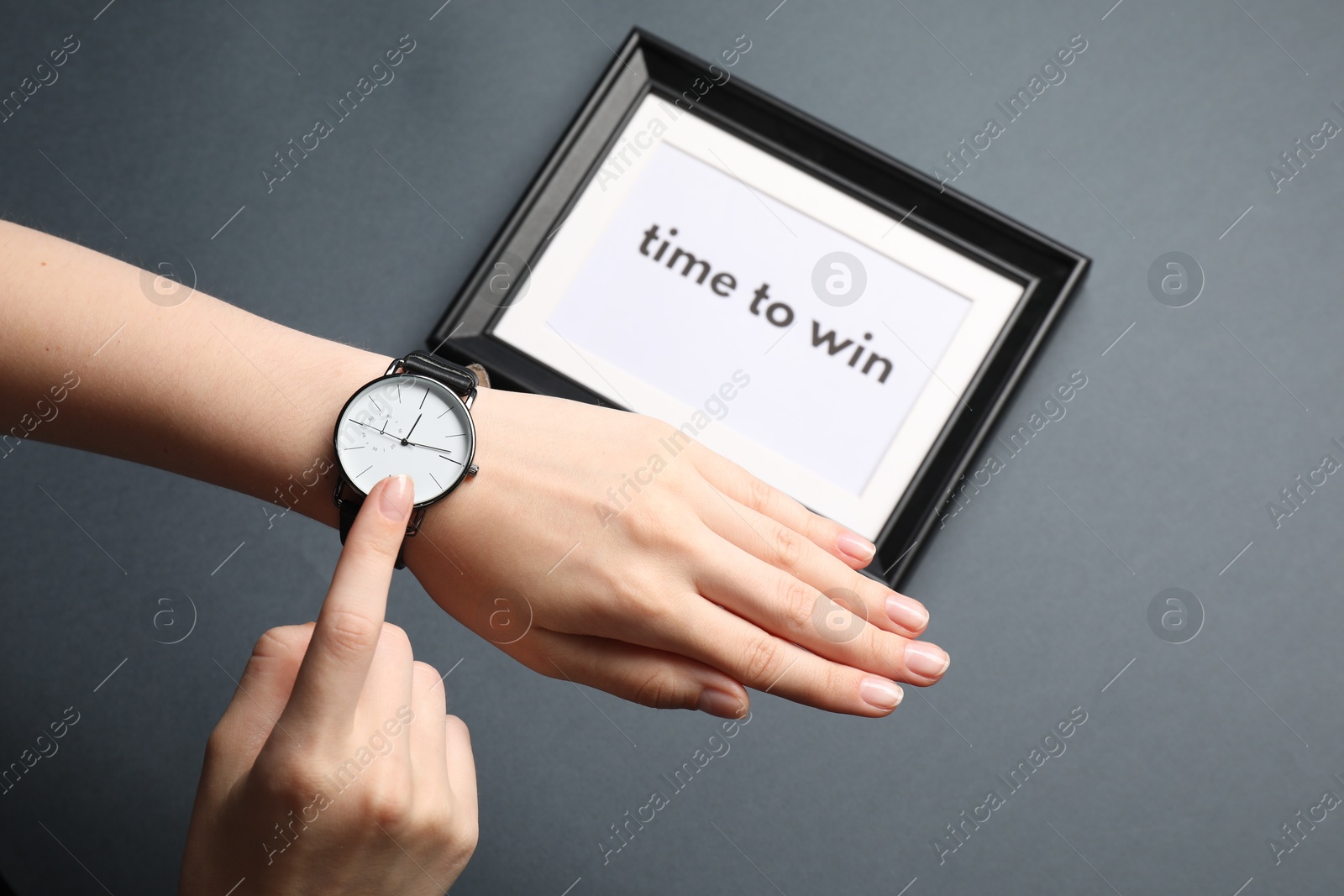 Photo of Woman pointing and watch and frame with words Time To Win on grey background, closeup