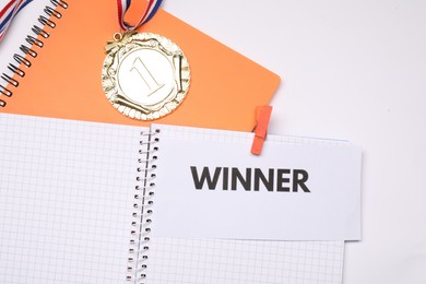 Photo of Notebooks with word Winner and golden medal on white background, flat lay