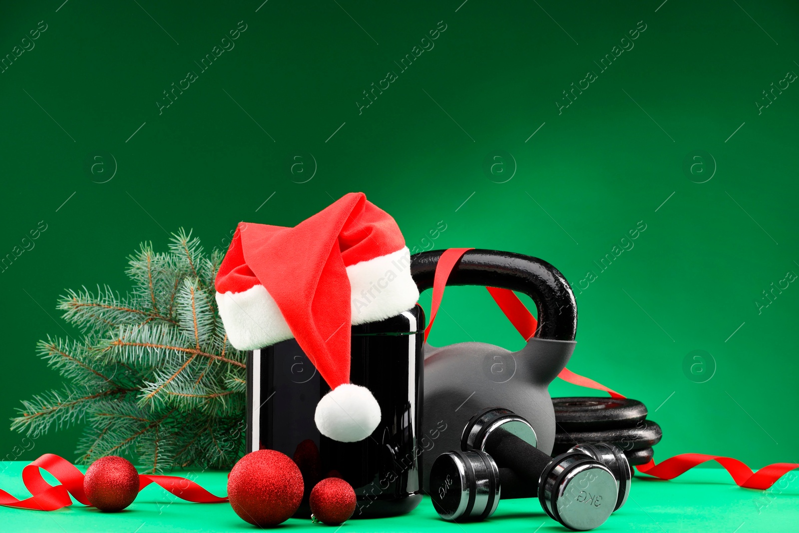 Photo of Dumbbells, kettlebell, container with supplement and Christmas decor on green background. Space for text