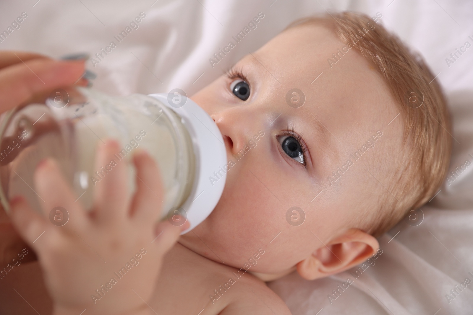 Photo of Cute little baby with bottle of milk on bed