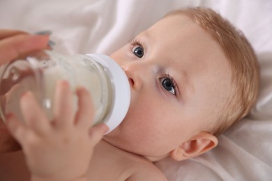 Photo of Cute little baby with bottle of milk on bed