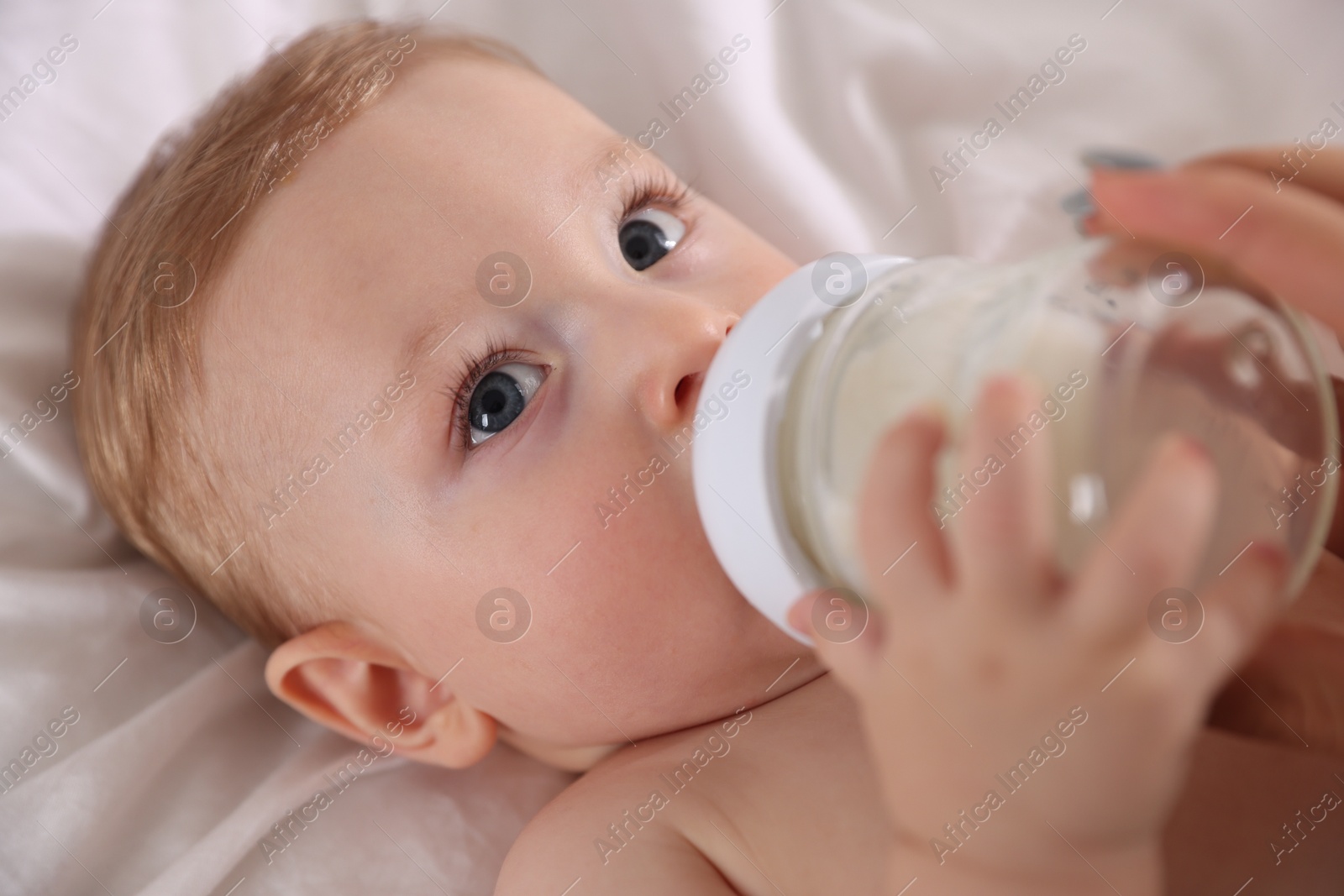 Photo of Cute little baby with bottle of milk on bed